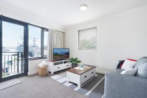 a living room with a couch and a tv at King Size Studio With Water View Walk To The City in Sydney