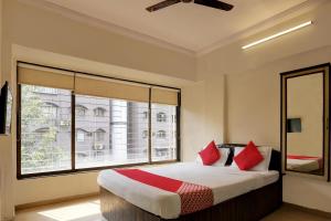 a bedroom with a bed with red pillows and a window at Hotel Lal Sai Residency in Mumbai