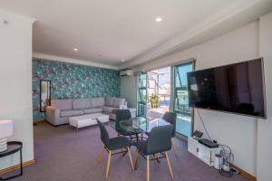 a living room with a couch and a tv at Chic Princes Wharf Studio - City View - Parking in Auckland