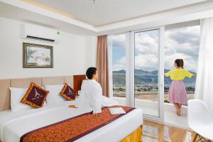 um homem e uma mulher a olhar pela janela de um quarto de hotel em Paris Nha Trang Hotel em Nha Trang