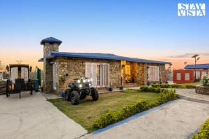 a stone house with a tractor in front of it at The Enchanted Forest with ATV Bike, Pet Friendly at Jim Corbett by StayVista in Kota Bāgh