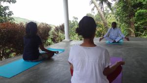 un grupo de tres personas sentadas en el suelo haciendo yoga en Monkey manor villa, Strathisla Tea Estate Bungalow en Matale