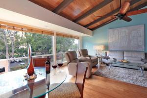 a living room with a ceiling fan and a glass table at Modern Kahana getaway in Kahana
