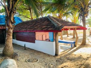 a small house on the beach with palm trees at Shim Beach Resort in Arugam Bay