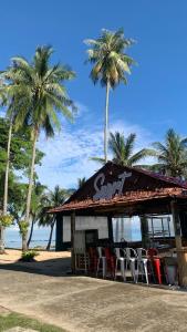 a restaurant with chairs and palm trees on the beach at Sea View Family Room at Nuvasa Bay Resort in Nongsa