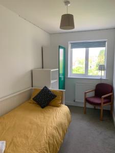 a bedroom with a bed and a chair and a window at The Chestnuts in Winscombe