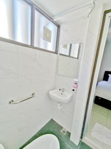 a white bathroom with a toilet and a sink at HOTEL APOLLO KAMPUNG BENGGALI in Butterworth