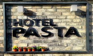 a sign on a brick wall with potted plants at Jinhae Pasta Hotel in Changwon