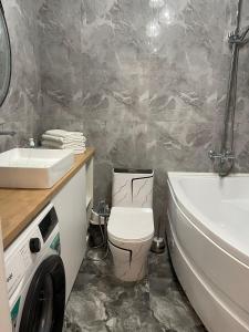 ein Badezimmer mit einem WC, einem Waschbecken und einer Waschmaschine in der Unterkunft Райский уголок in Almaty