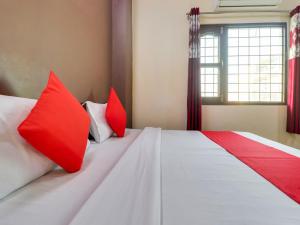 a bedroom with two red pillows on a bed at OYO Hotel Kesariya Bhawan Home Stay in Dehradun