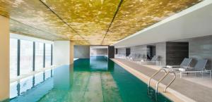 a swimming pool with a gold ceiling in a building at Le Meridien Zhengzhou in Zhengzhou