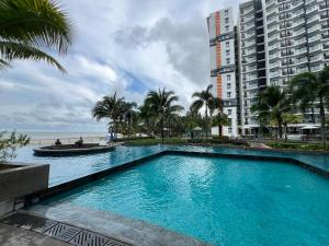 uma piscina em frente a um edifício e ao oceano em VitaminSEA3 Seaview 6PAX Studio Netflix A-8-13A em Kuantan