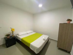 a bedroom with a bed with a green and yellow blanket at Emporium Medellín Laureles in Medellín