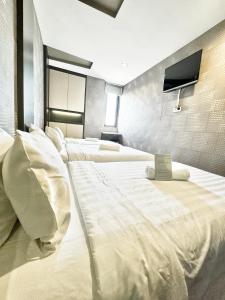 1 dormitorio con 2 camas con sábanas blancas y TV en Chariton Hotel Nusa Bestari, en Johor Bahru