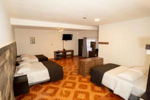 um quarto de hotel com duas camas e uma televisão em Hotel Luna de Plata Aeropuerto em Quetzaltenango