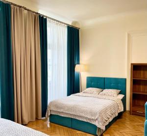 sypialnia z niebieskim łóżkiem i oknem w obiekcie Apartamenty i Studia HERBARIUM w Krakowie