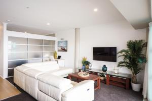 a living room with a white couch and a tv at Princes Wharf - Luxury in Auckland