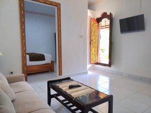 a living room with a couch and a table and a mirror at Rumah Bali Kelating in Krambitan