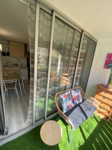 a balcony with a wicker chair and a table at Studio La Baleine Rose Centre Cap D'Agde in Cap d'Agde