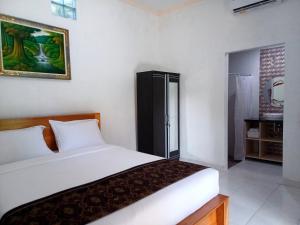 a bedroom with a white bed and a bathroom at Rumah Bali Kelating in Krambitan