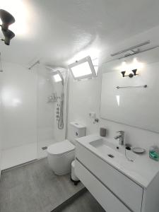 a white bathroom with a toilet and a sink at Haus mit fantastischem Meerblick in Mácher