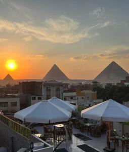 een dakterras met tafels en parasols bij zonsondergang bij King of Pharaohs INN pyramids in Caïro