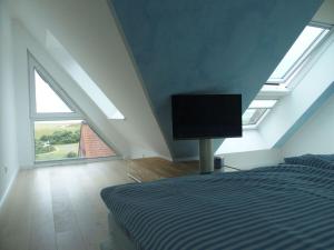 a bedroom with a bed with a television in it at Lütje Sandbank Modern retreat in Juist