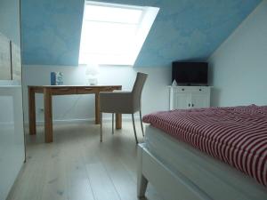 Schlafzimmer mit einem Bett, einem Schreibtisch und einem Fenster in der Unterkunft Lütje Sandbank Modern retreat in Juist