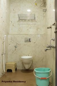 a bathroom with a toilet and a bucket in it at Priyanka Residency in Kanchipuram