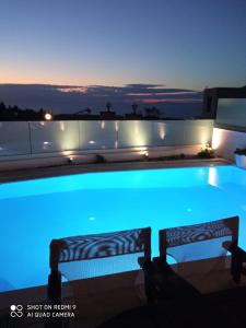 dos bancos sentados junto a una piscina por la noche en Villas Goudis, en Tsoukaladhes