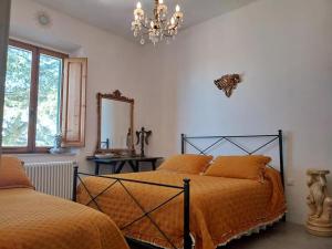 a bedroom with two beds and a mirror and a chandelier at Villino Sole di Toscana con terrazza panoramica e giardino in Monterotondo