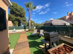 a backyard with a grill and a lawn with a palm tree at Can Guerrero pet friendly a 500 metros de la playa! in Calas de Mallorca
