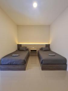 a bedroom with two beds and a small table at Merpati inn hotel in Dompu