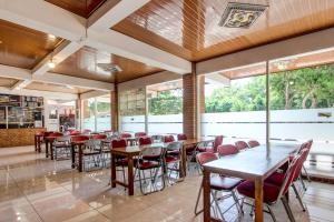 a dining room with tables and chairs and windows at Collection O 93742 Sidodadi Hotel Dan Resto in Yogyakarta