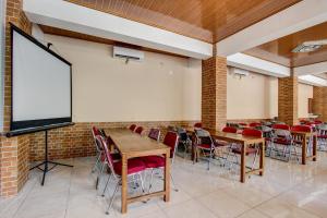 uma sala de aula com mesas e cadeiras e uma tela de projeção em Collection O 93742 Sidodadi Hotel Dan Resto em Yogyakarta