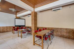 una sala de conferencias con mesas y sillas y una pantalla de proyección en Collection O 93742 Sidodadi Hotel Dan Resto en Yogyakarta