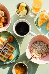 a table with plates of breakfast foods and a cup of coffee at Hôtel Du Golfe in Ajaccio