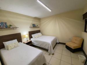 a hotel room with two beds and a chair at Mi casa es tu casa. in Quetzaltenango