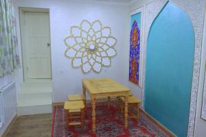 a table and chairs in a room with a wall at Hotel ALISHER in Bukhara