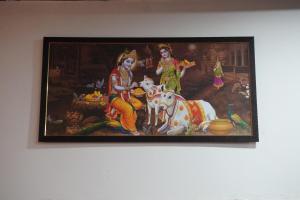 uma pintura de duas mulheres com uma vaca na parede em Radha Rani Dham (Near Iskcon Temple) em Vrindavan