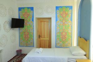 a bedroom with two beds and a tv on the wall at Hotel ALISHER in Bukhara