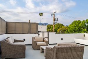 een patio met rieten stoelen en tafels op een dak bij Four Bedrooms Luxurious Townhouse in Los Angeles