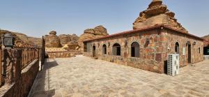 un antiguo edificio de piedra con una pared de piedra en Red Mountain Farm, en Al Ula