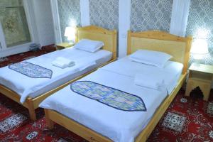 two beds in a hotel room with white sheets at Hotel ALISHER in Bukhara