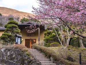 uma casa com escadas que levam a uma porta com flores cor-de-rosa em Hanare Yado Yosizumi em Izu