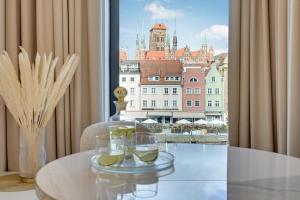 uma mesa com copos de vinho e vista para a cidade em Deo Plaza Riverside & Radisson SPA by Downtown Apartments em Gdansk