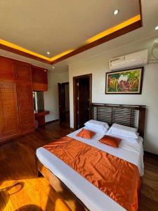 a bedroom with a large bed with an orange blanket at Camiguin Lanzones Resort in Mambajao
