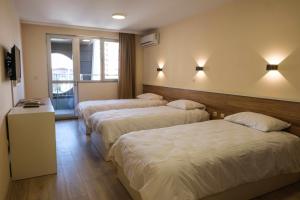 a hotel room with three beds and a window at HOTEL BAYKO in Plovdiv