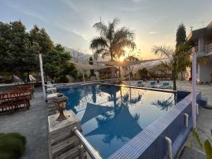a large swimming pool with a sunset in the background at Hills and Horizon Resort in Benighāt