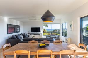uma sala de estar com uma mesa e um sofá em Cable Bay Views em Oneroa